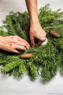 Çiçekçi köknar dalları bir Noel çelenk yapar. Kadın ellerinin en iyi görünümü. Düz yatıyordu. Şerit dekorasyon