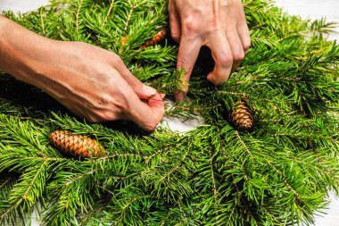 Çiçekçi köknar dalları bir Noel çelenk yapar. Kadın ellerinin en iyi görünümü. Düz yatıyordu. Şerit dekorasyon