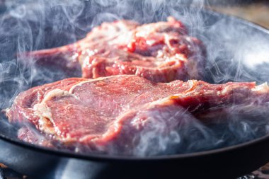 Izgara tavada bir beaf biftek duman ve buhar yükselişi