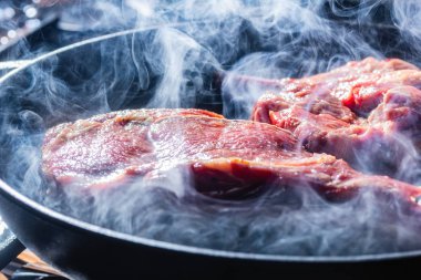 Izgara tavada bir beaf biftek duman ve buhar yükselişi