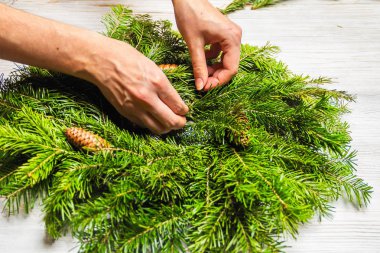 Çiçekçi köknar dalları bir Noel çelenk yapar. Kadın ellerinin en iyi görünümü. Düz yatıyordu. Şerit dekorasyon