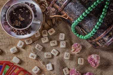 İzoterik kehanet ve tahmin kavramı. Tarot kartları, rünler, fincanda kahve telveleri, tespih, kurumuş bir çiçek eski bir göğsün arka planında..