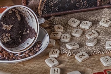 İzoterik kehanet ve tahmin kavramı. Tarot kartları, rünler, fincanda kahve telveleri, eski bir göğsün arka planında bir masanın üzerindeki tespih..