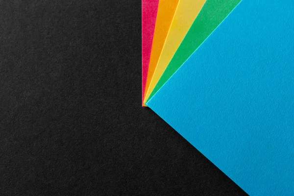 Farbige Ecken aus Regenbogenpapier auf schwarzem strukturiertem Hintergrund. Geschäftskonzept. Layout für Design. Kopierraum — Stockfoto
