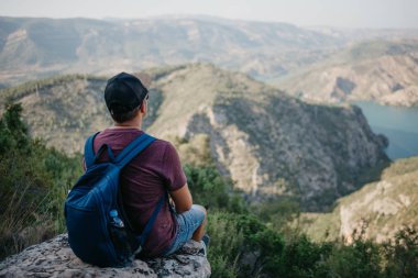 Zümrüt Nehri ile güzel kanyon yukarıda kayada İspanya'da günbatımı üzerinde oturan sırt çantası olan bir adam. Adam serüveni.