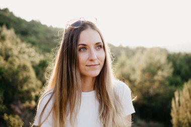 Şirin kız T-shirt ve yeşil bitkilerle günbatımı İspanya arka plan üzerinde tepe üzerinde bir sürü arasında sağ tarafında seyir güneş gözlüğü. Gezgin dağlarda. 