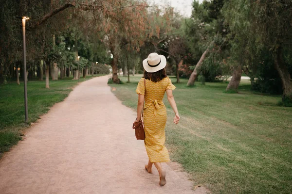 夕方にはスペインの公園で帽子で歩いている美しい若いブルネット女性 — ストック写真
