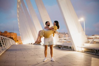 Sakallı şık adam güzel esmer kız gece İspanya köprüde onun kollarında tutar
