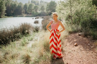 Dağ Gölü bataklık poz kırmızı ve beyaz elbiseli şık bir güzel sarışın Bayan. Sizi bekliyoruz. İspanya