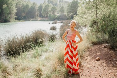 Bir şık mutlu sarışın Bayan dağ Gölü bataklık poz kırmızı ve beyaz elbiseli. Sizi bekliyoruz. İspanya
