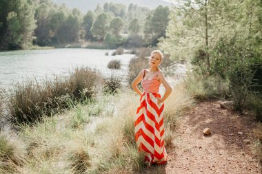 Dağ Gölü bataklık poz kırmızı ve beyaz elbiseli şık bir güzel sarışın Bayan. Sizi bekliyoruz. İspanya