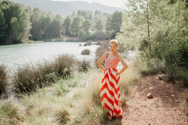 Bir şık sevimli sarışın Bayan dağ Gölü bataklık poz kırmızı ve beyaz elbiseli. Sizi bekliyoruz. İspanya