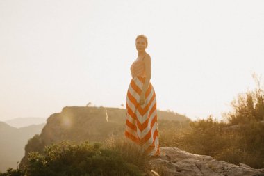 Turuncu güneş ışığı altında Antik Kanyon kenarına poz zarif çekici genç bir kadın. İspanya