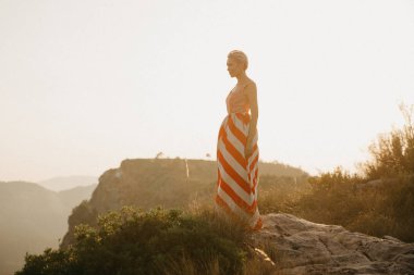 Turuncu güneş ışığı altında Antik Kanyon kenarına poz rahat bir kız. İspanya