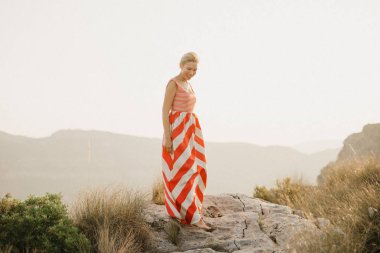 Turuncu güneş ışığı altında Antik Kanyon kenarına poz rahat güzel bir kadın. İspanya