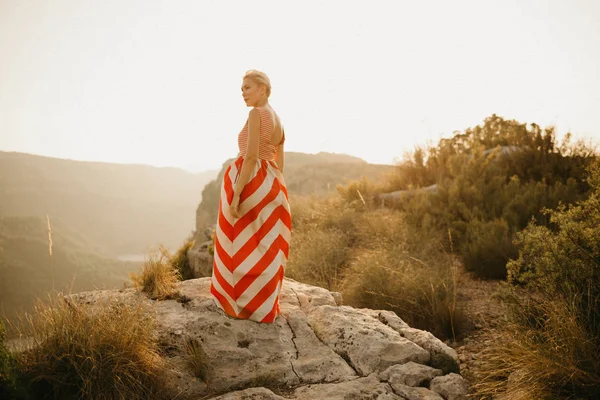オレンジ色の夕日に古代峡谷の背中でポーズ赤いドレスでの集中白人若い女性 スペイン — ストック写真