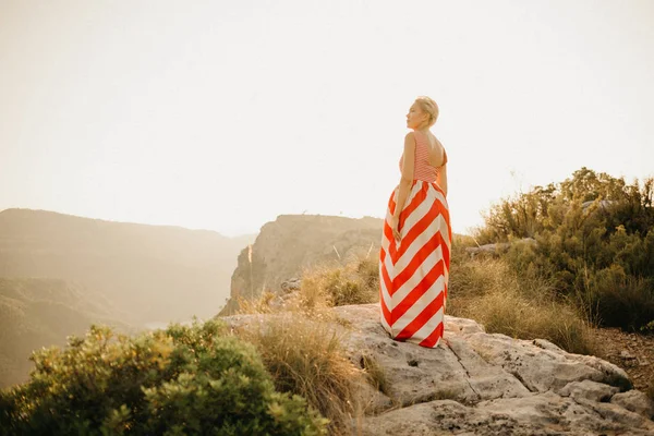 オレンジ色の夕日に川と古代峡谷の背中でポーズ赤いドレスでブロンドの女の子 スペイン — ストック写真