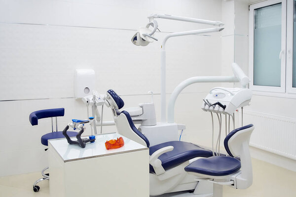 New dental chair with white and blue furniture. Dentists office