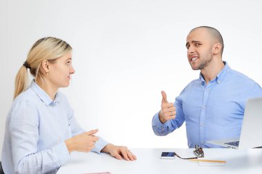 Beyaz arka plan ile Ofis Masası tarafından acımasız patron sarışın beyaz meslektaşı yakınındaki şık güneş gözlüğü gülümsüyor ile mavi gömlekli oturur.