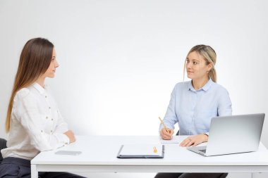 Beyaz arka plan ile Ofis Masası tarafından mavi gömlek görüşmeler yeni bir esmer kadın çalışan sarışın beyaz kadın patron oturur.