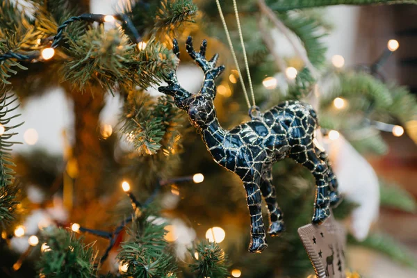 Christmas decoration of black and gold deer on a green Christmas tree with warm yellow garland.
