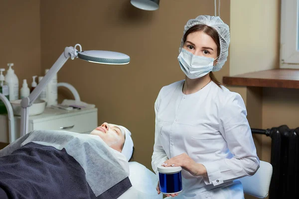 Eine Kosmetikerin Mit Medizinischer Gesichtsmaske Posiert Mit Einem Pflegeprodukt Der — Stockfoto