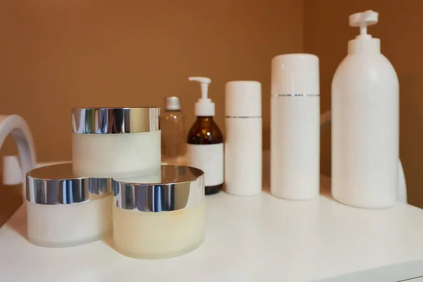 All kinds of skincare products on a white trolley cart in a cosmetology office.