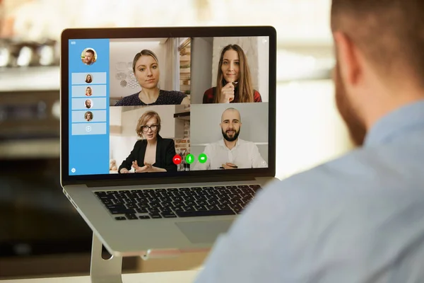 Uzaktan çalışan ve evdeki bir laptopta iş hakkında iş konuşmalarını dinleyen bir adamın arka planı. İnternetteki bir toplantıda bir iş ekibiyle bilgisayar ekranının yakın bir fotoğrafı..
