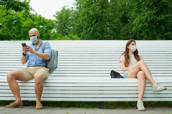 휴대폰을 반대편에 코로나 바이러스가 퍼지는 거리를 남자와 공원에서 사교적 거리에서 — 스톡 사진