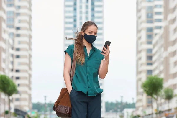 Una Mujer Joven Con Una Mascarilla Médica Lee Noticias Teléfono —  Fotos de Stock