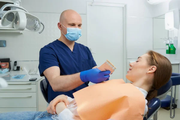 Łysy Dentysta Średnim Wieku Wybiera Kolor Zębów Dla Pacjentki Przed — Zdjęcie stockowe