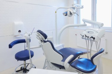 Beyaz ve mavi mobilyaları, diş sandalyeleri, yüksek hızlı matkapları olan yeni bir dişçi bürosu. Dişçinin ofisi..