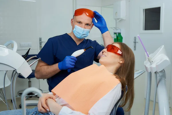 Dentista Uma Máscara Facial Médica Óculos Proteção Segurando Uma Luz — Fotografia de Stock
