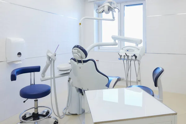 The new interior of a dental office with white and blue furniture, dental chair, high-speed drills. Dentist's office.