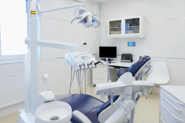 The new interior of a dental office with white and blue furniture, dental chair, high-speed drills. Dentist\'s office.