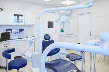 Beyaz ve mavi mobilyaları, diş sandalyesi, ıslak değirmen ve öğütme makinesi, intraoral tarayıcısı, polimerleşme ışığı olan modern bir diş hekimliği. Dişçinin ofisi. Diş Laboratuvarı.