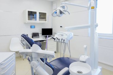 Beyaz ve mavi mobilyalı, dişçi koltuğu ve bilgisayarı olan modern bir dişçi ofisi. Dişçinin ofisi. Diş Laboratuvarı.