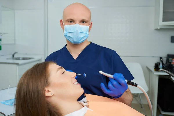 Dentista Calvo Con Una Mascarilla Médica Sostiene Espejo Dental Perfora —  Fotos de Stock