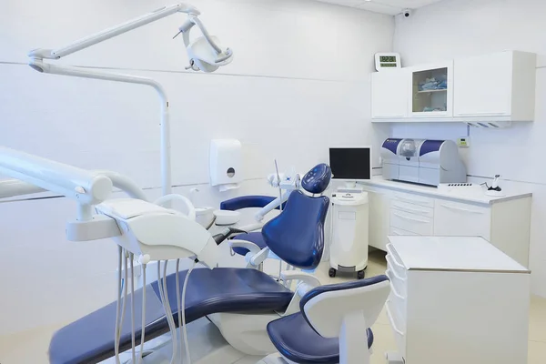 The new interior of a dental office with white and blue furniture, dental chair, wet milling, and grinding machine, intraoral scanner, a led polymerization light. Dentist's office. Dental laboratory.