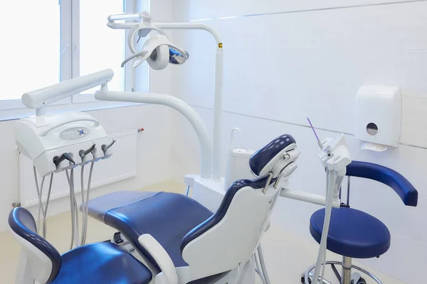 The new interior of a dental office with white and blue furniture, dental chair, drills. Dentist\'s office.