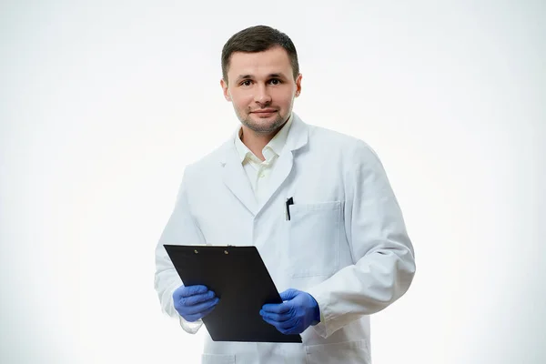 白衣を着た優しい男性の白人医師と青い使い捨て医療用手袋は 診断付きの患者カードを持つ段ボールを保持しています 科学者は白地に隔離されている — ストック写真