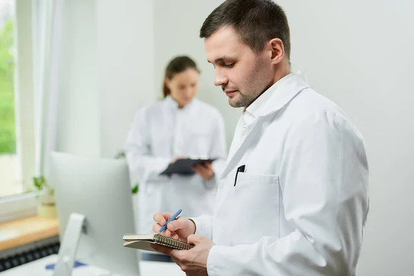 Médico Caucásico Con Cuaderno Bolígrafo Registra Historia Clínica Del Paciente — Foto de Stock