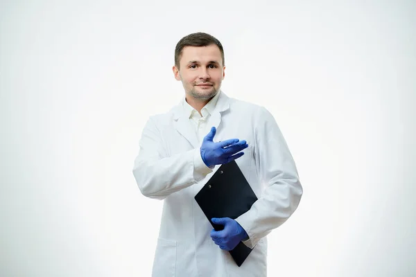 白衣を着た笑顔の男性医師と青い使い捨て医療用手袋が片手で段ボールを持っているのに対し 指差している 科学者は白地に隔離されている — ストック写真