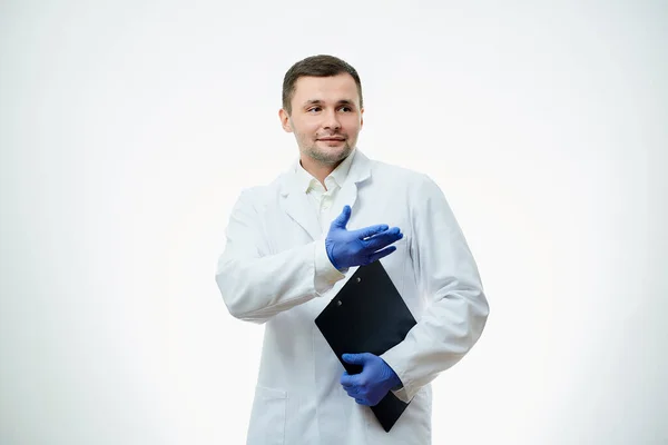 白い研究室のコートと青い使い捨て医療用手袋の優しい男性医師が一方で段ボールを保持しており もう一方が指しています 科学者は白地に隔離されている — ストック写真