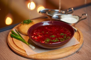 Bir Ukrayna borsch 'unun fotoğrafı pampuşka, yeşil soğan ve ekşi krema bir tepside bir restoranın masasında..