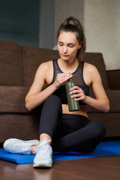 Sportowa Dziewczyna Czarnym Kombinezonie Treningowym Odpoczywa Otwiera Zieloną Aluminiową Butelkę — Zdjęcie stockowe