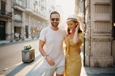 Sakallı bir adam, şapkalı bir kız arkadaşının eli ve İspanya 'da yakası sarkan sarı bir elbiseyle beline sarılıyor. Valencia 'da gün batımında bir çift sevgili..