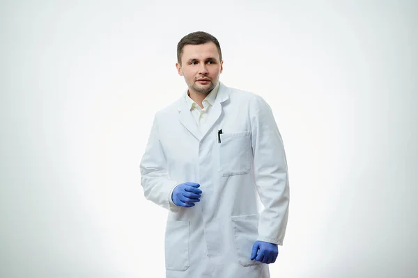 白い研究室のコートに青い使い捨て医療用手袋の男の原因不明の医者が待っている 科学者は白地に隔離されている — ストック写真