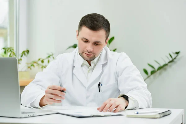 Médico Caucásico Serio Con Una Bata Blanca Laboratorio Está Sentado — Foto de Stock