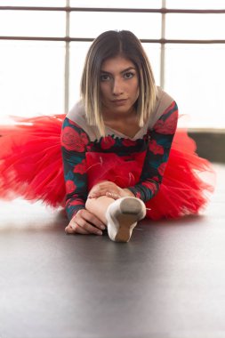 Bale tutu ile güzel latin kadın yerde bir bölünme yapıyor bacağına uzanan